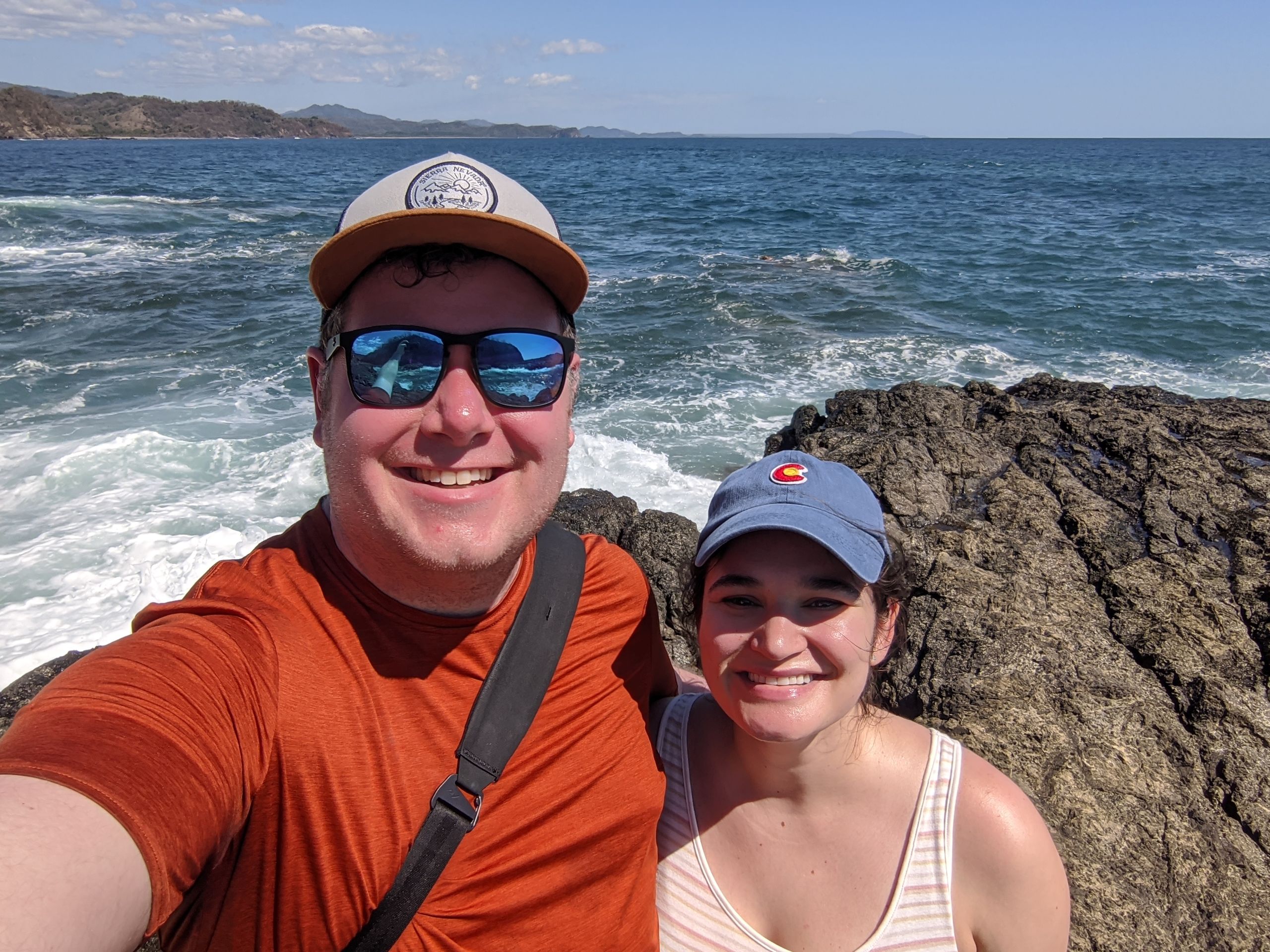 Nat and Mel on a cliff above the pacific ocean at high tide.