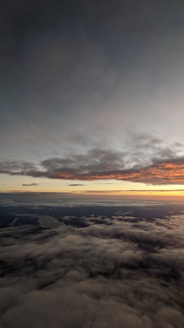 Golden sunset viewed from an airplane with cloud layers below and sky above.