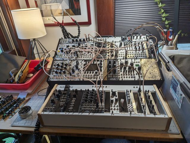 Large modular synthesizer setup with rows of modules and many patch cables on a desk.
