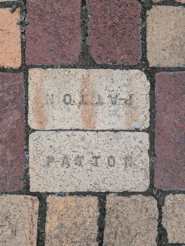 Close-up of vintage brickwork with two white stone bricks engraved with text and numbers among red clay bricks.