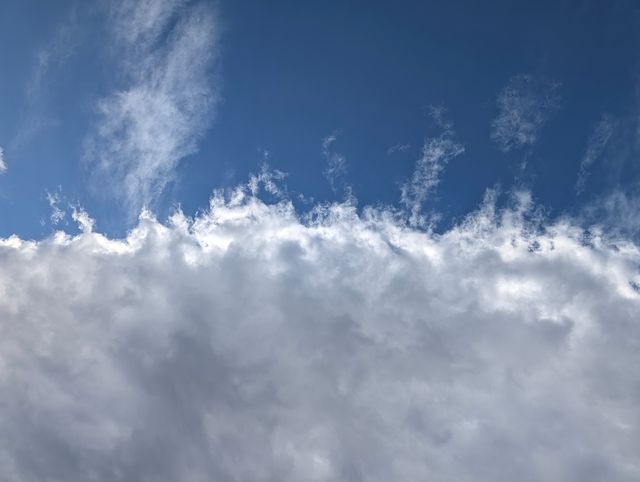 Bright blue sky with wispy white clouds layered across the frame.