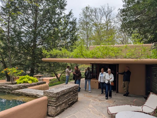 Visitors standing on Fallingwater's flagstone terrace near the plunge pool, beneath the cantilevered roof