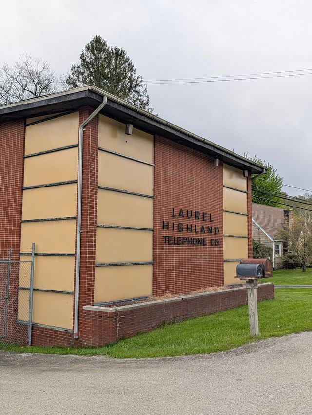 The brick side of the Laurel Highland Telephone Co. building, with cream-colored panels and a mailbox at the curb